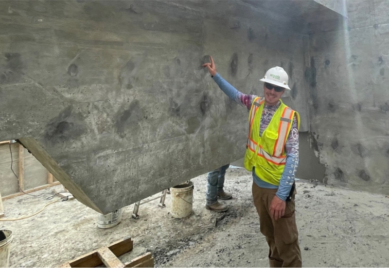 A construction worker standing next to a concrete wall.