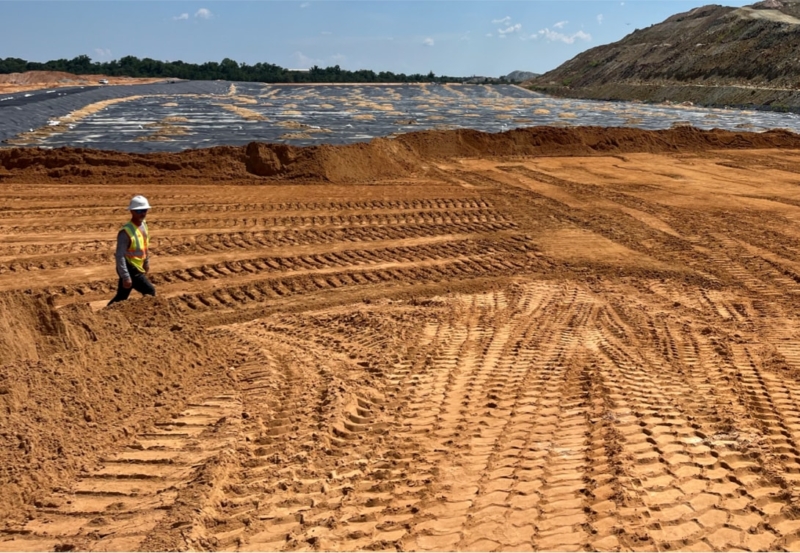 A construction worker standing in front of a sand pit.