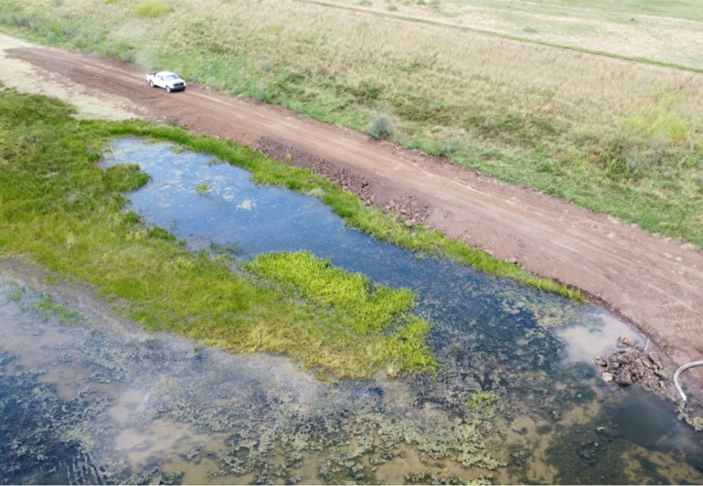 An aerial view of a truck driving down a dirt road.